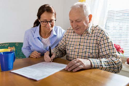 Caregiver and elderly man reading paperwork